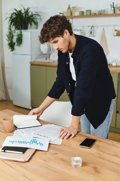 A young man with curly hair reviews his notes intently in a stylish home setting. — Stock Photo