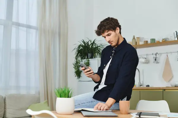 Handsome young man sits comfortably in his stylish apartment, focused on his smartphone. — Stock Photo