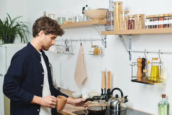 Young man with curly hair enjoys his morning routine while brewing coffee at home. — Stock Photo