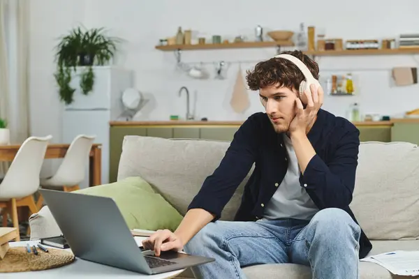 Jovem com cabelo encaracolado se concentra em seu laptop em um espaço vivo brilhante e moderno. — Fotografia de Stock