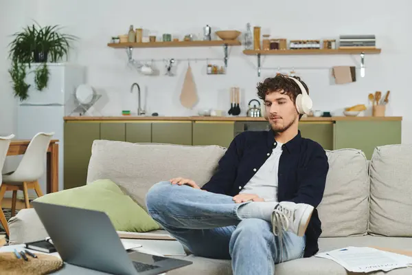 Jovem bonito e de cabelos encaracolados ouve música, relaxando em seu ambiente acolhedor em casa. — Fotografia de Stock
