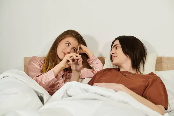 Two young people share playful smiles and intimate conversation under soft blankets at twilight. — Stock Photo