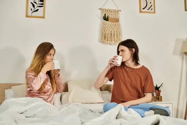 Dois jovens gostam de bebidas quentes enquanto conversam em um quarto moderno e pensativo. — Fotografia de Stock