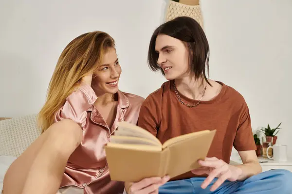 A chic pair enjoys a relaxed day at home, engaging deeply in a shared book while smiling. — Stock Photo