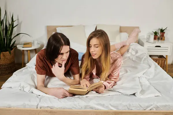 Zwei stylische junge Menschen entspannen sich auf einem Bett, in ein Buch vertieft, während sie von viel Grün umgeben sind. — Stockfoto