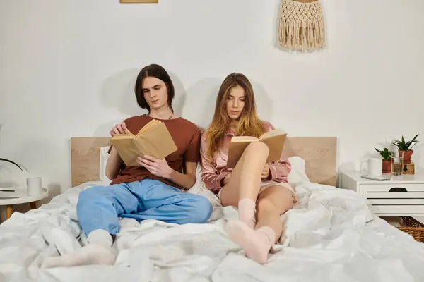 Two young individuals relax in a stylish bedroom, engrossed in their books and enjoying the moment. — Stock Photo