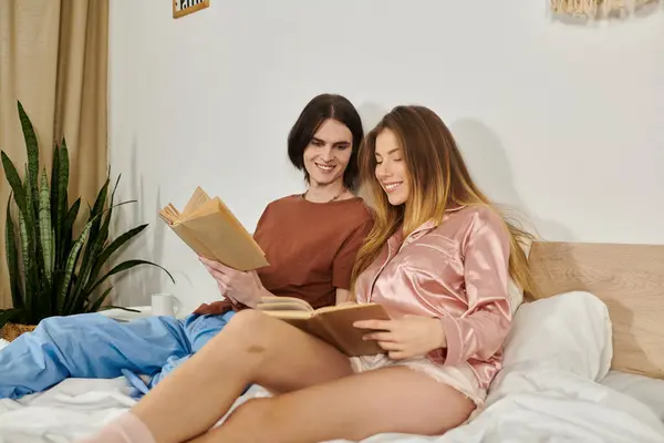 Two young individuals share a cozy moment, reading together in a tranquil bedroom while smiling. — Stock Photo