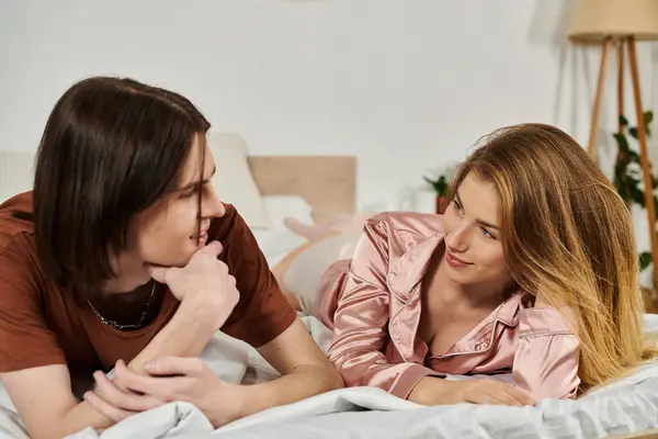 Pareja joven relajarse y conectarse en su dormitorio de moda mientras comparte risas y sonrisas. - foto de stock