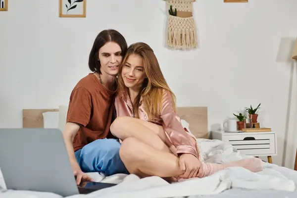 A young couple relaxes in a chic bedroom, sharing smiles and ideas while using a laptop. — Stock Photo