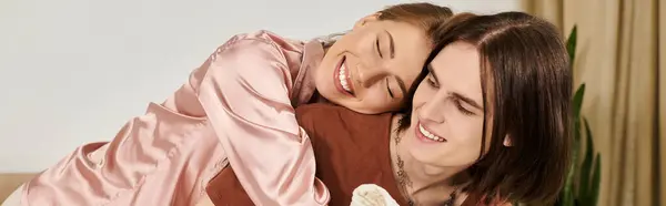A young couple enjoys a playful embrace on a cozy sofa, radiating joy and warmth in their space. — Stock Photo