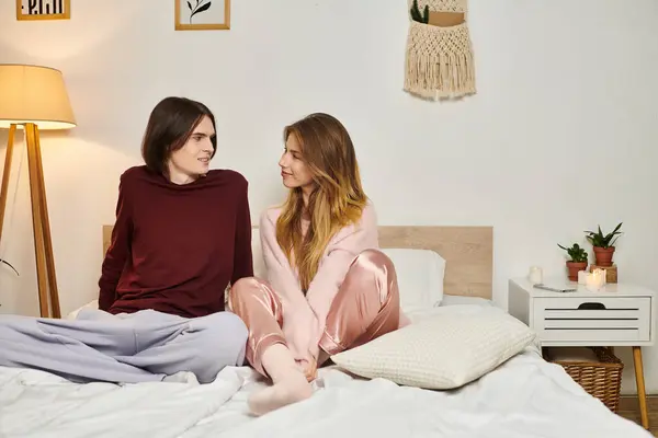 Dos jóvenes comparten la risa y la conversación íntima en un dormitorio de moda lleno de calor. - foto de stock