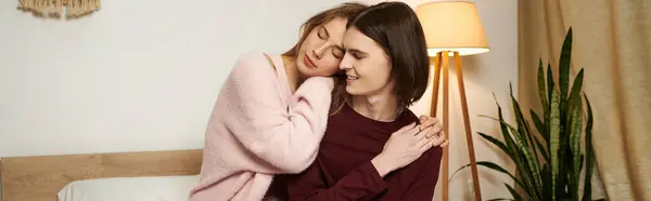 A young couple shares an intimate embrace in a softly lit bedroom, radiating warmth and affection. — Stock Photo