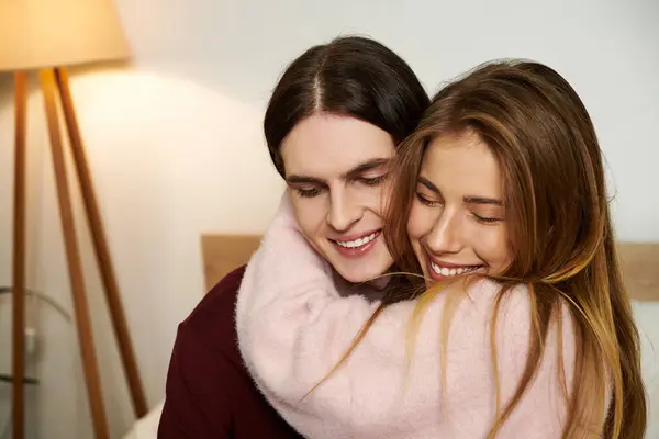 Dos jóvenes adultos disfrutan de un momento alegre juntos, envueltos en los brazos del otro, sonriendo brillantemente. — Stock Photo