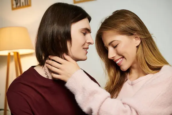 Young couple enjoying a sweet interaction in a stylish living room filled with warm light. — Stock Photo