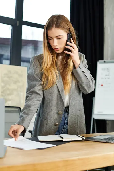 Un joven profesional en atuendo elegante revisa papeles mientras está de guardia en un espacio de trabajo elegante. - foto de stock