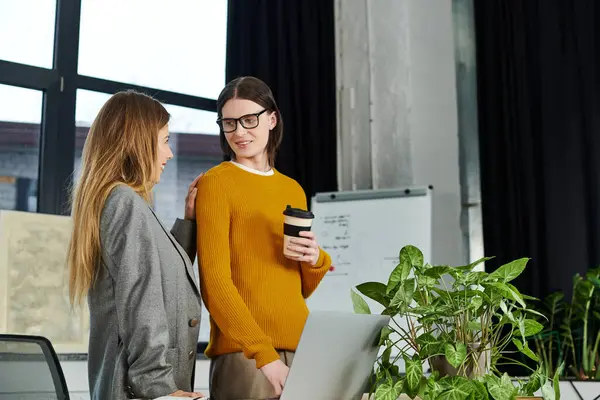 Due giovani si scambiano idee in un ufficio moderno con piante abbondanti e luce naturale. — Foto stock