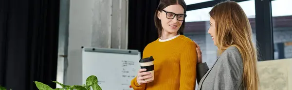 Two young people engage in cheerful conversation while sipping coffee in a modern interior. — Stock Photo