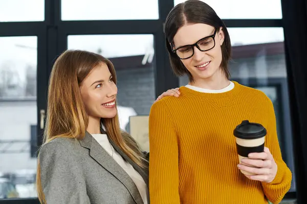 Two stylish young individuals share a joyful moment in a warm cafe filled with light. — Stock Photo