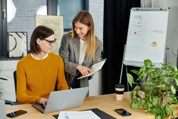 Deux personnes chics s'engagent dans une discussion créative tout en travaillant sur un ordinateur portable ensemble. — Photo de stock