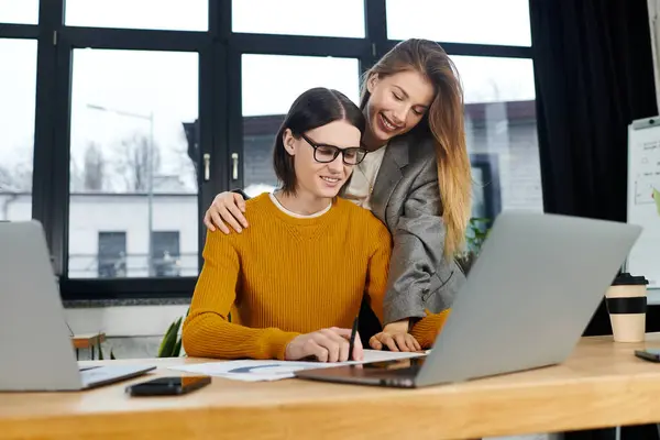Dos jóvenes compañeros de trabajo disfrutan del vibrante ambiente de una oficina elegante mientras se centran en sus tareas. - foto de stock