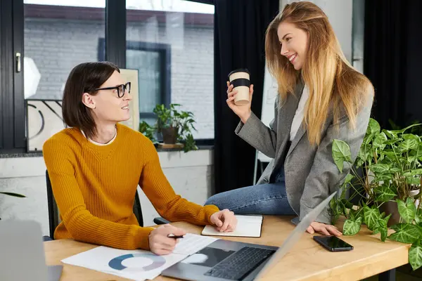 Two young people engage in a lively discussion while surrounded by plants in a modern office. — Stock Photo