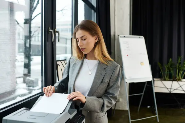 A chic young woman handles printing tasks in a stylish office space filled with natural light. — Stock Photo