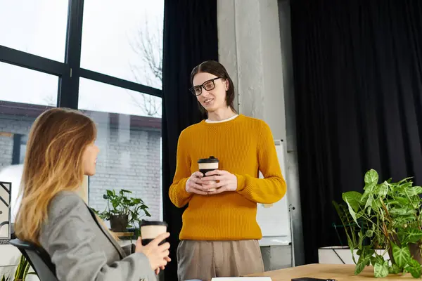 Zwei junge Menschen tauschen sich beim Kaffeetrinken in stilvoller Büroatmosphäre aus. — Stockfoto