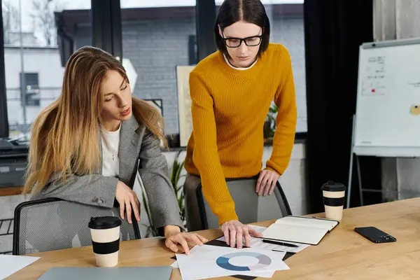 Two young people intensely discuss and analyze project materials at a stylish office workspace. — Stock Photo