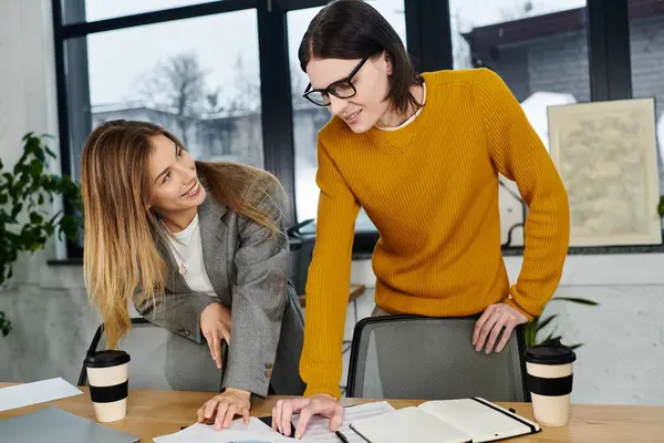 Two young professionals share ideas and laughter while working on a project in a modern office. — Stock Photo