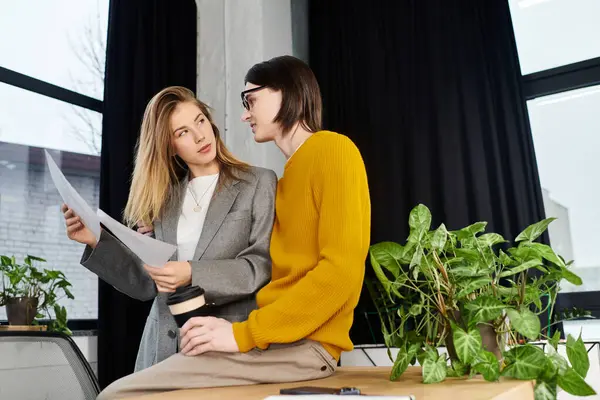 Engaged young couple collaborates on creative ideas in a stylish workspace surrounded by greenery. — Stock Photo