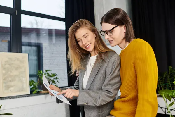 Two young individuals share ideas while reviewing documents in a cozy, modern environment. — Stock Photo