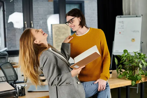 Two stylish young individuals enjoy a light moment while discussing a book in a creative workspace. — Stock Photo