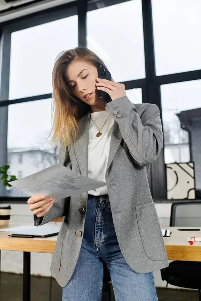 Stylish young woman takes a business call while reviewing important papers in the office. — Stock Photo