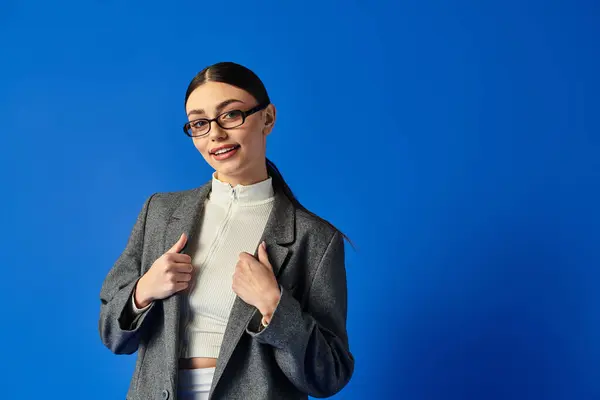 Bright blue backdrop showcases a joyful young woman, exuding confidence and happiness. — Stock Photo