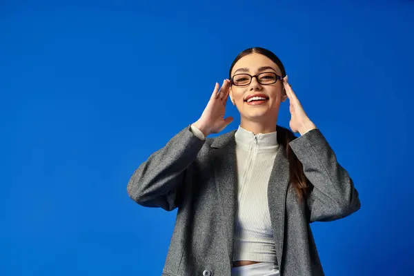 A young, beautiful woman is smiling broadly while touching her temples in delight. — Stock Photo
