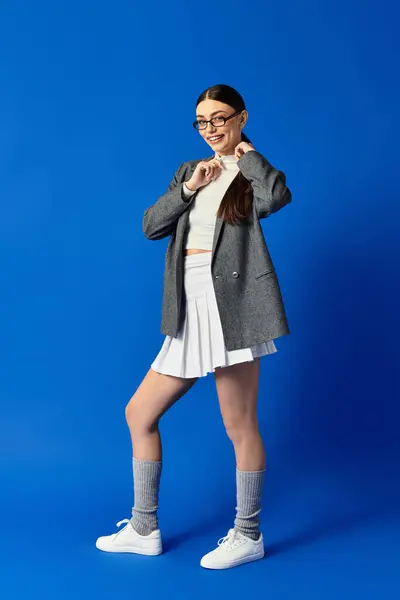 Una joven mujer emana confianza vistiendo un atuendo elegante, golpeando una pose juguetona con una sonrisa. - foto de stock