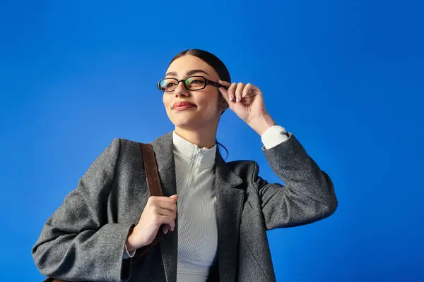 A young woman with glasses expresses confidence while flaunting her fashionable outfit. — Stock Photo