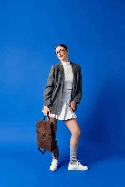 A young beautiful woman showcases her fashionable attire with a bright smile and a stylish bag. — Stock Photo