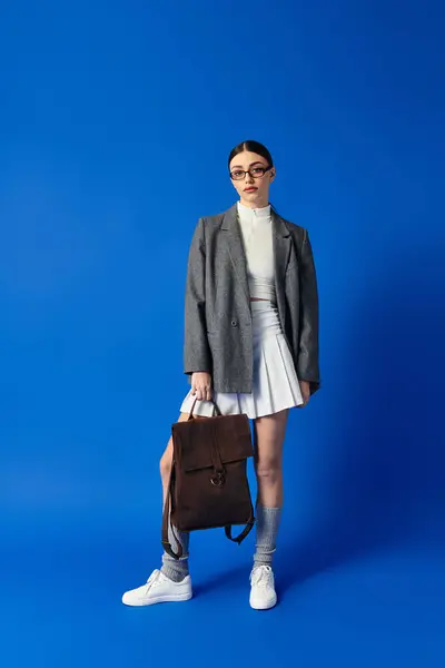 A young woman expresses emotions through her fashion, holding a backpack gracefully. — Stock Photo