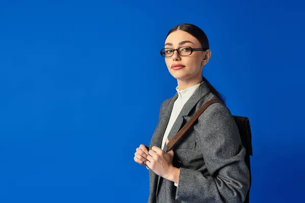 Молода жінка в окулярах впевнено ділиться своїми емоціями на яскраво-блакитний фон. — стокове фото