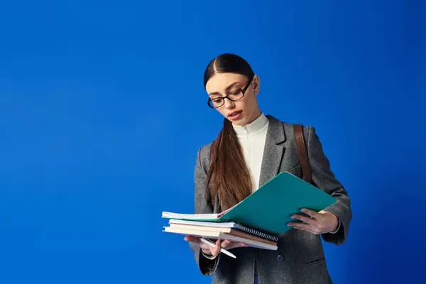 Emotionally engaged young woman reviews her notes while surrounded by colorful study materials. — Stock Photo