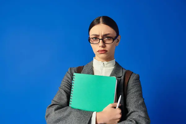 Una giovane donna si alza fiduciosa con un blocco note e una penna, trasmettendo una forte presenza emotiva. — Foto stock