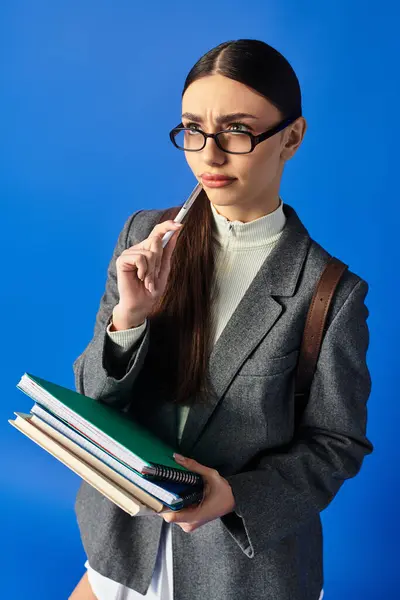 A young beautiful woman in a stylish outfit holds books while contemplating her next move. — Stock Photo