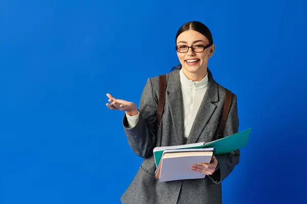 A cheerful young woman holds multiple folders while engaging with enthusiasm in a lively setting. — Stock Photo