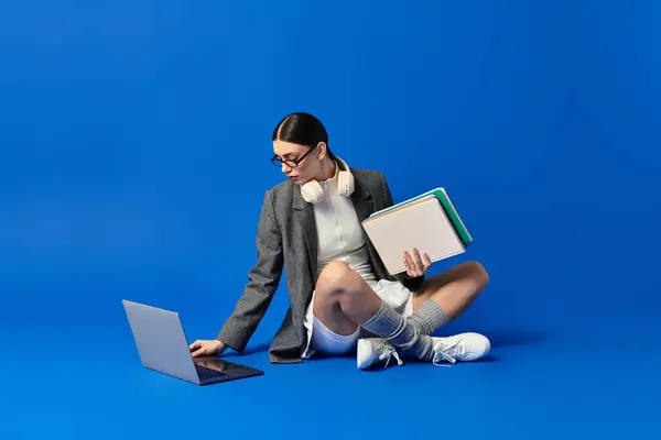 Young beautiful woman with headphones focuses on her laptop, surrounded by colorful notebooks. — Stock Photo