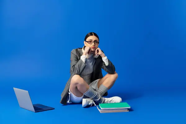 A young woman expresses deep emotions while seated on the floor, surrounded by books and a laptop. — Stock Photo