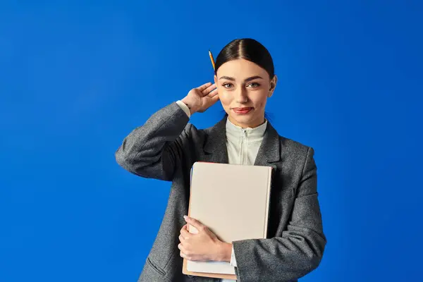 A young beautiful woman looks thoughtful while holding a notebook and pencil, exuding confidence. — Stock Photo