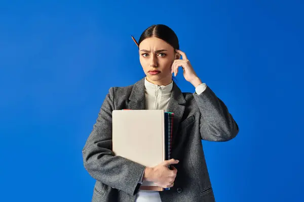 Zerstrittene junge Frau blickt nachdenklich, während sie tief in Gedanken einen Stapel Ordner umklammert. — Stockfoto