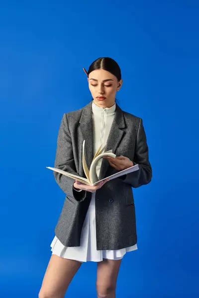 A thoughtful young woman in a stylish blazer engages with the pages of a book, lost in her thoughts. — Stock Photo