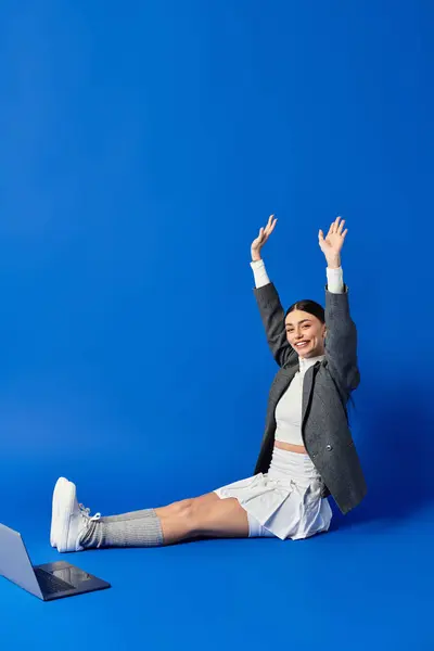 A beautiful young woman expresses excitement with her arms raised in celebration, dressed stylishly. — Stock Photo